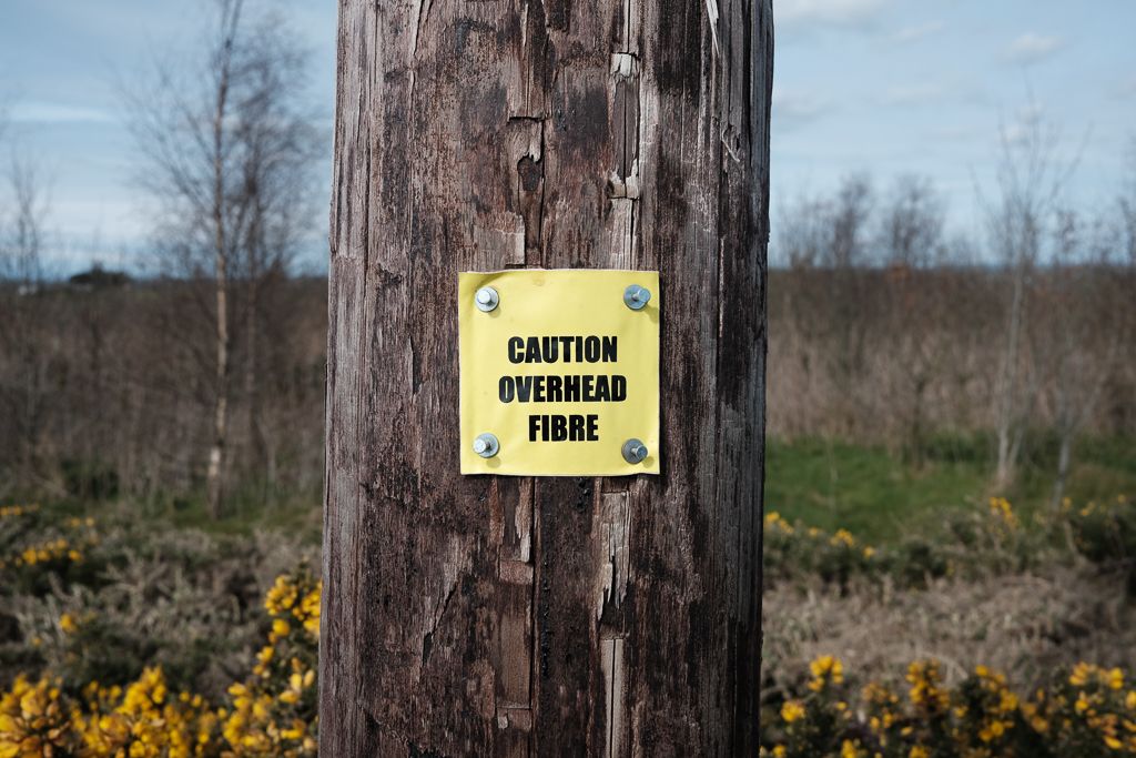 A telegraph pole with a yellow fibre overhead label.