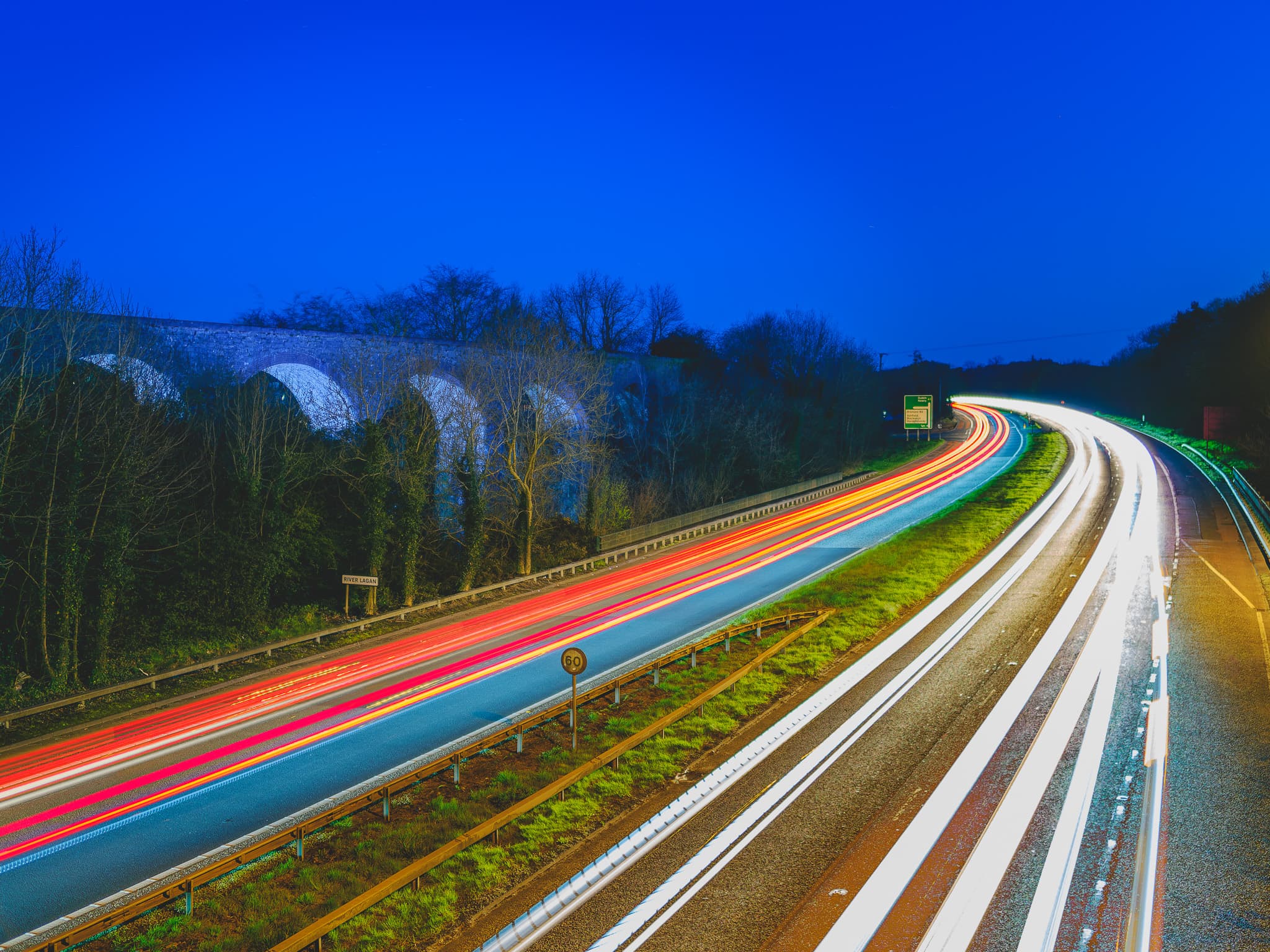 Car light trails streaming by an old railway viaduct