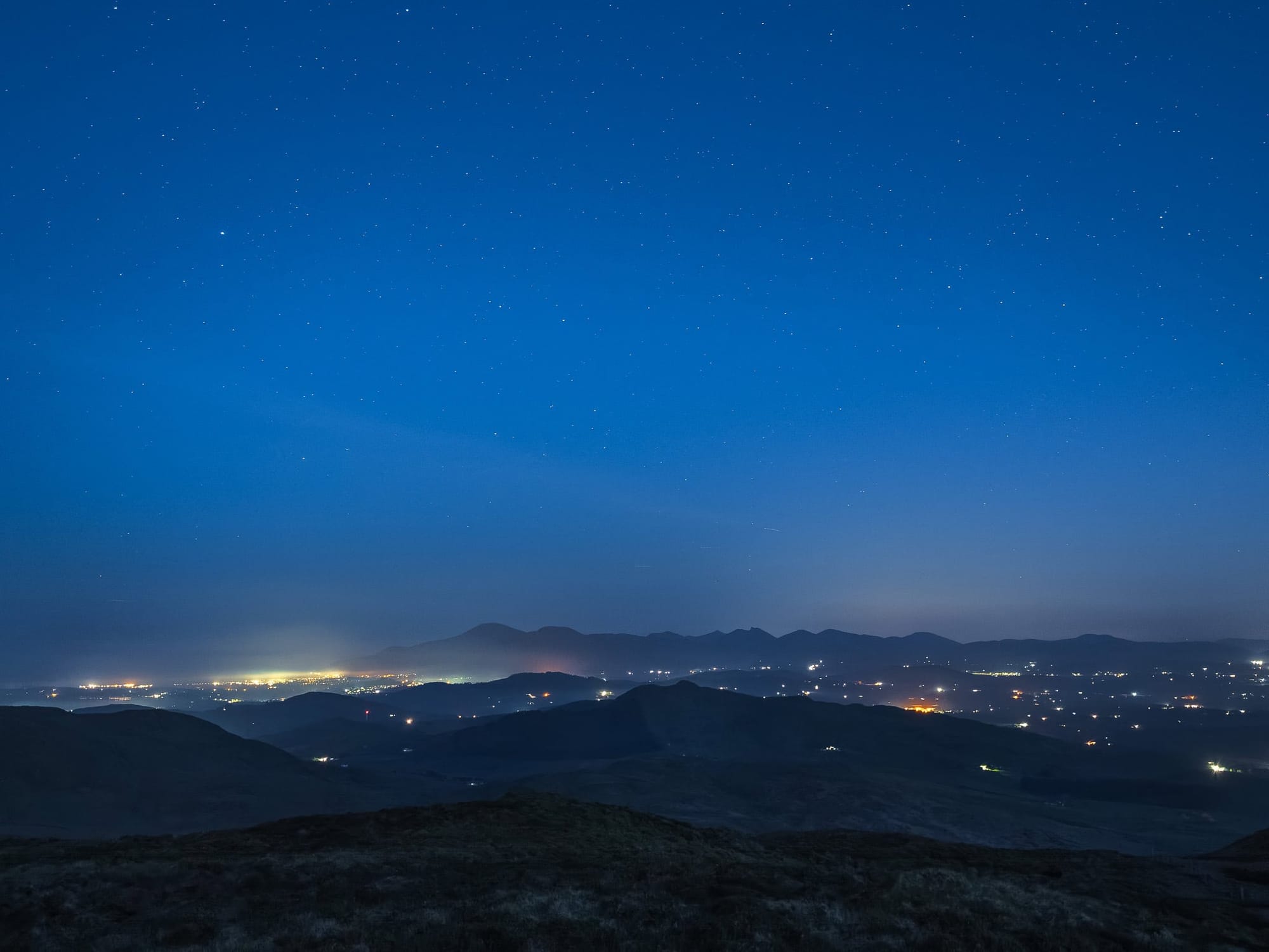 A late night view of the Mourne range of mountains, twinkling lights and stars