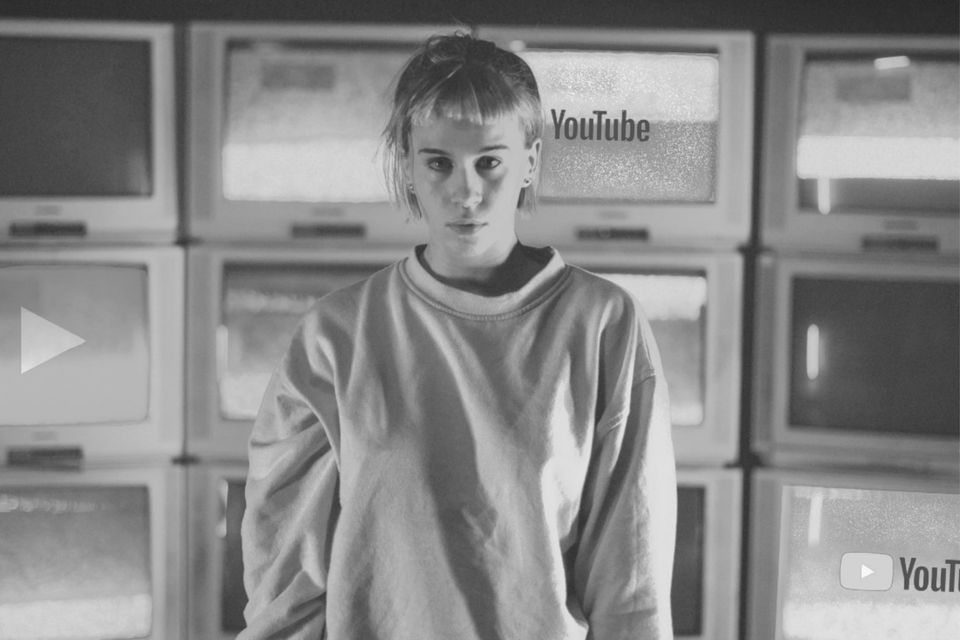 An upset girl surrounded by televisions.