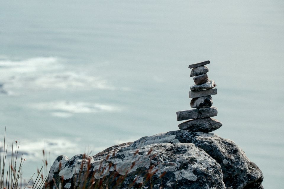 Stacked stones standing on a rock with the sea in the background