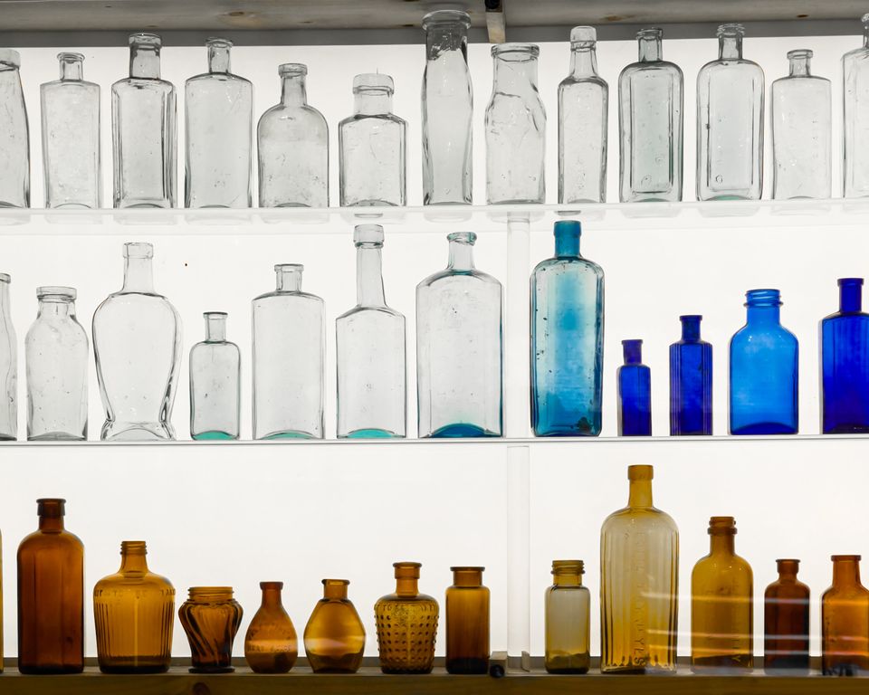 Antique bottles displayed on a wall with backlighting
