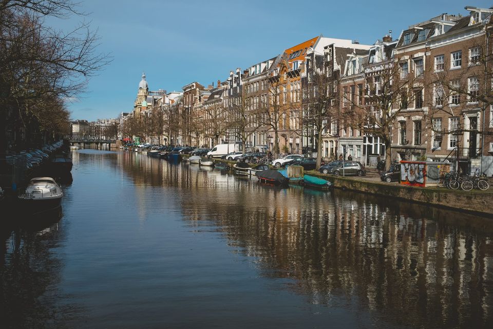 A view of one of Amsterdam's many canals with still water and boats tied up 