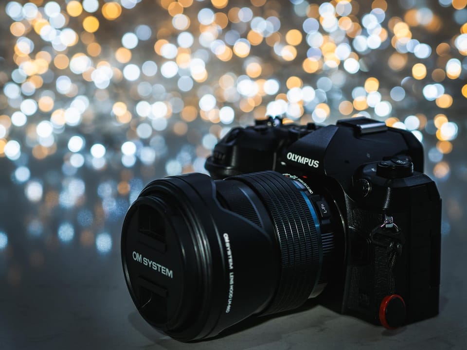 The OM System OM-1 Micro Four Thirds Camera with sparkly Bokeh lights in soft focus